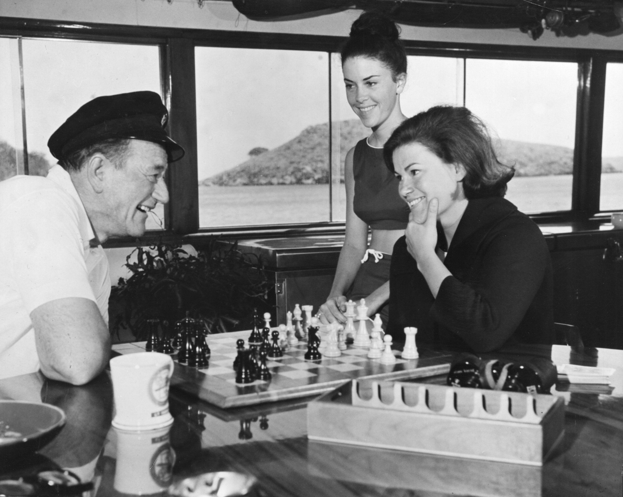 John Wayne with his daughter Melinda aboard Wild Goose enjoying a game of chess.