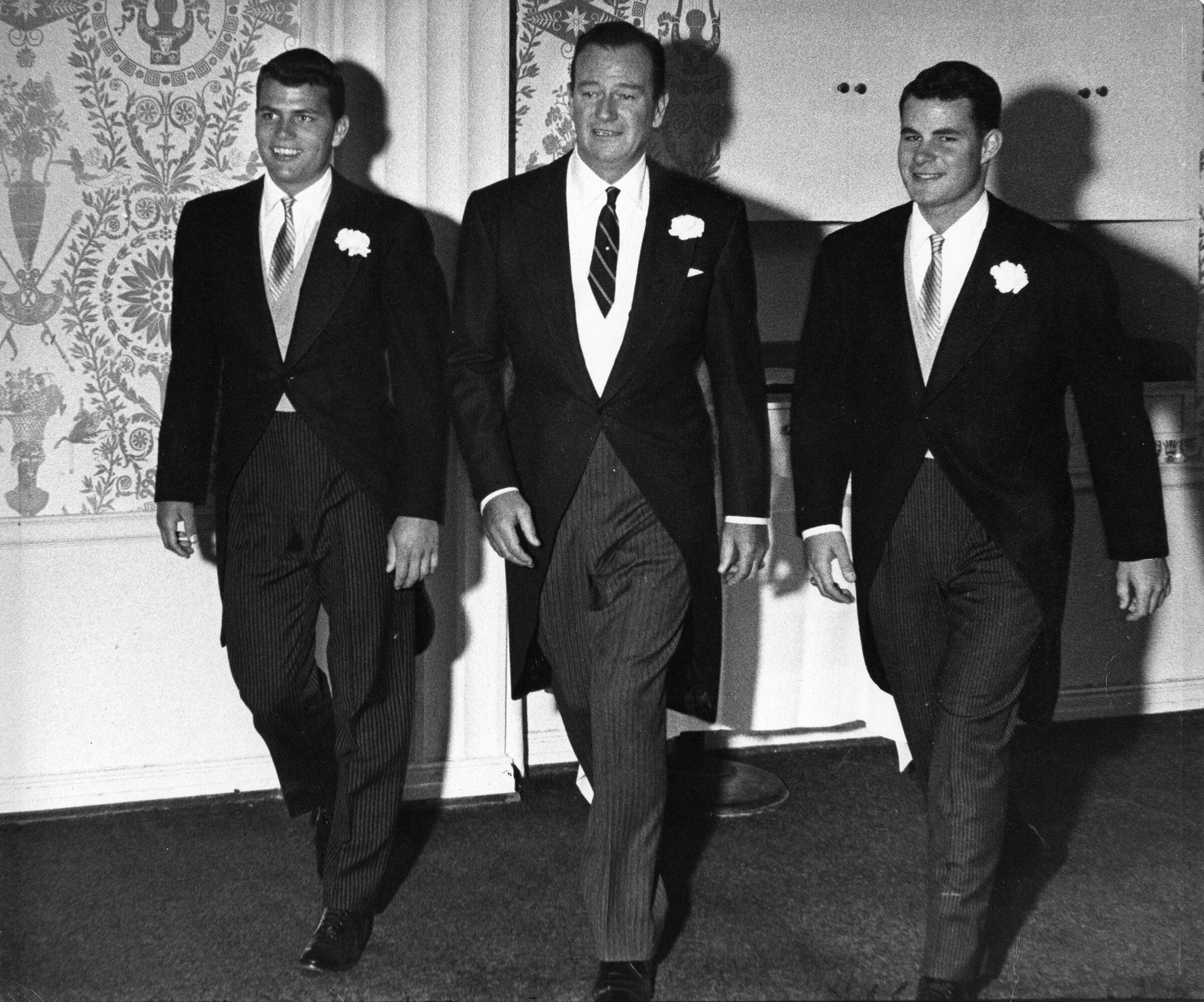 John Wayne with his sons Patrick (left) and Michael (right) make an entrance at Antonia Wayne’s wedding.