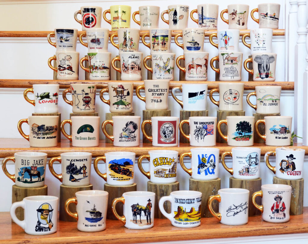 A selection of John Wayne Cast & Crew Gold Handle Mugs, each commemorating a specific film with a distinctive gold-painted handle