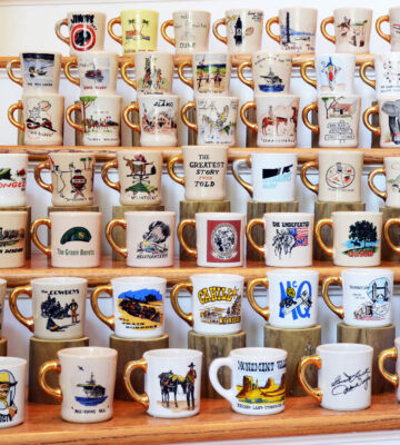 A selection of John Wayne Cast & Crew Gold Handle Mugs, each commemorating a specific film with a distinctive gold-painted handle